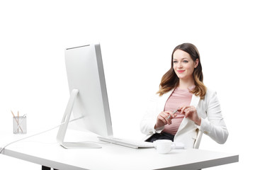 Smiling young businesswoman. Portrait of young financial assistant sitting at desk in front of computer and while working on business report. Isolated on white background.