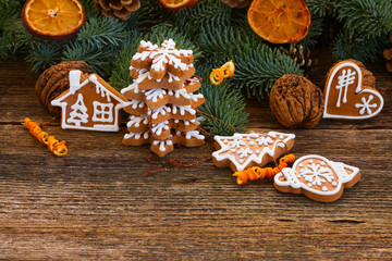 christmas gingerbread cookies with fir tree twigs and oranges on wooden table