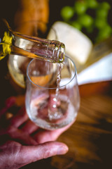 Man is pouring white wine into the glasses