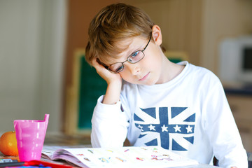 Frustrated kid boy with glasses at home making homework