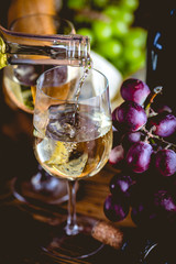 Man is pouring white wine into the glasses