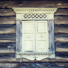 Abandoned house. Window frame with architraves and shutters. Facade of an old log cabin. Journey to...