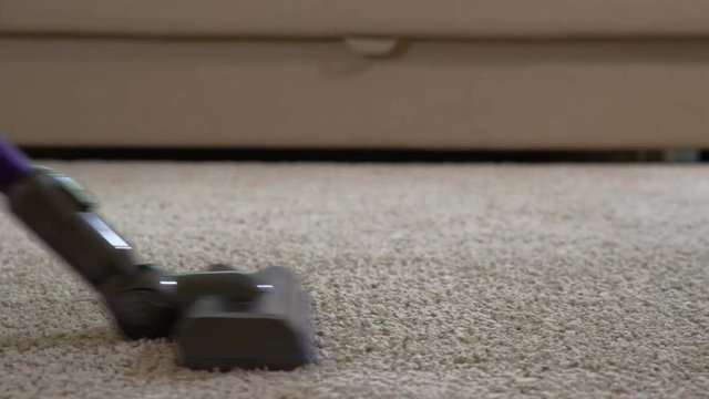 A woman uses a vacuum cleaner to clean the carpet.