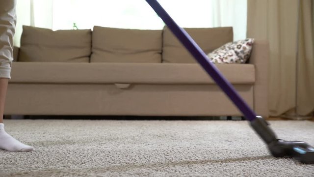 A Woman Uses A Vacuum Cleaner To Clean The Carpet.