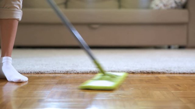 Woman cleaning parquet floors in the living room. Close-up.
