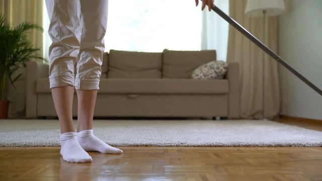 Woman cleaning parquet floors in the living room. Close-up.