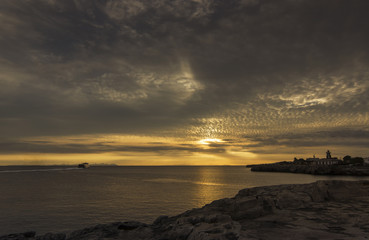Amazing sunset over the sea with a ship and  lighthouse in foreground. Menorca, Spain