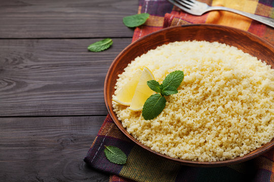 Couscous with mint and lemon in plate on wooden vintage table. Copy space for text.