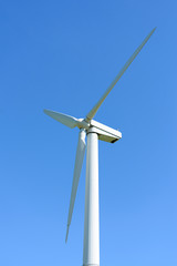 Wind generator in the meadows, on a background of blue sky.