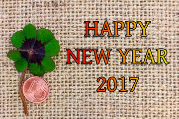Glücksklee und ein Cent liegen auf Stoff für Silvester 2017