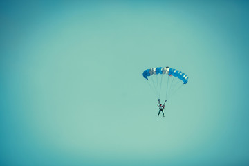 Skydiver On Colorful Parachute In Sunny Clear Sky.
