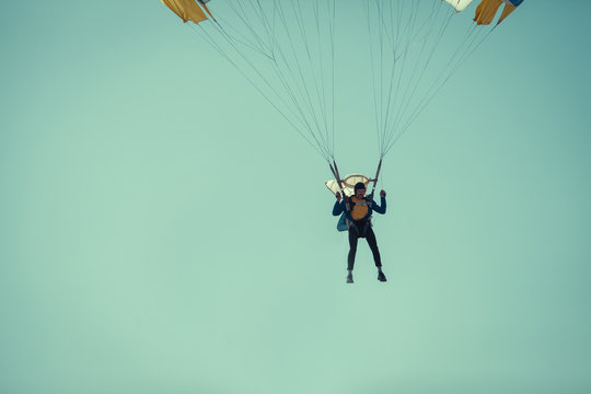 Skydiver On Colorful Parachute In Sunny Clear Sky.
