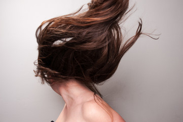 Fototapeta premium Stop action photograph of a beautiful woman with brunette hair creating motion with her hair.