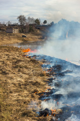 Burning dry grass on the river bank. Spring. Near the village.