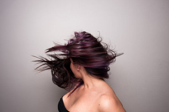 Stop action photograph of a beautiful woman with brunette hair creating motion with her hair.
