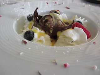 Melted chocolate ball with zabaglione cream, whipped cream, raspberries and blueberries