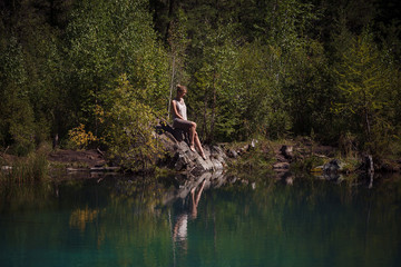 Fototapeta na wymiar Young woman sitting near blue mountain lake