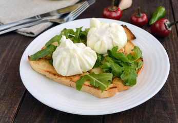 Boiled eggs in a pouch (poached) on crispy toast and green arugula leaves. Dietary breakfast.