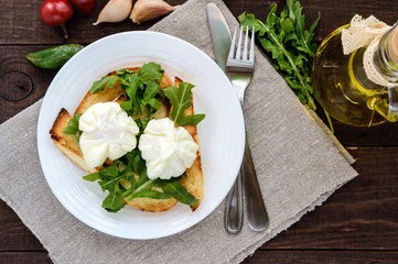Boiled eggs in a pouch (poached) on crispy toast and green arugula leaves. Dietary breakfast. The top view
