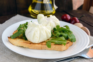 Boiled eggs in a pouch (poached) on crispy toast and green arugula leaves. Dietary breakfast.