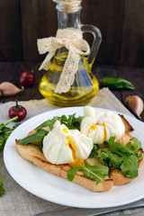 Fototapeta na wymiar Boiled eggs in a pouch (poached) on crispy toast and green arugula leaves. Dietary breakfast.