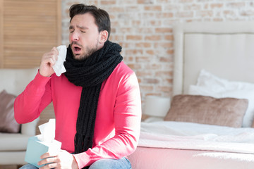 Ill young man sneezing