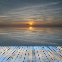 perspective wood plank floor on sunset sky sea with reflex backg