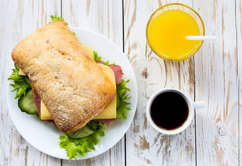 Chiabatta sandwich, cup of coffee and orange juice