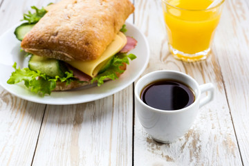 Chiabatta sandwich, cup of coffee and orange juice