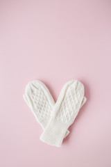 beauty white feminine knitted mittens on pink background. flat lay, top view