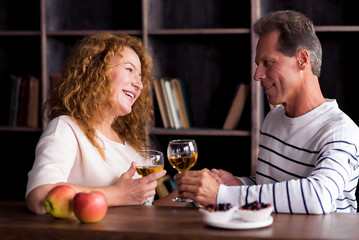 Delighted grandparents looking at each other and holding hands