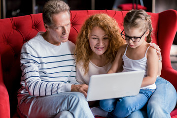 Girl sitting in front of the laptop with her grandparents