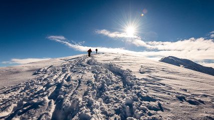 Naklejka na ściany i meble tourists enjoying high mountains in snow on a sunny day
