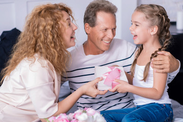 Obraz na płótnie Canvas Amazed little girl getting a birthday gift from her grandparents