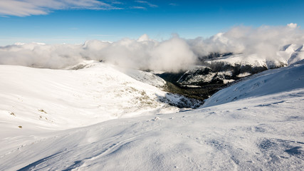 Obraz premium mountain tops in winter covered in snow with bright sun and blue