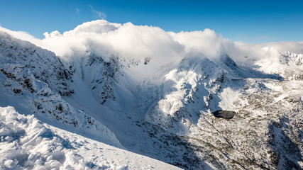 Obraz premium mountain tops in winter covered in snow with bright sun and blue