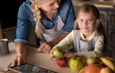 Cute girl having fun with her mother in the kitchen
