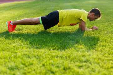 Fototapeta na wymiar Sporty caucasian man doing push up on lawn