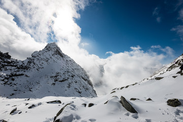 mountain tops in winter covered in snow with bright sun and blue