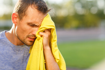 Athletic man wipes his face with yellow towel