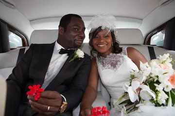 Poster Happy newlyweds of beautiful bride woman in car for wedding black couple © OceanProd