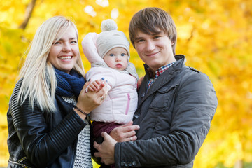 Young family with daughter on hand in autumn park