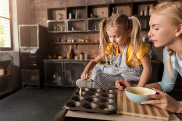 Concentrated girl helping her mother preparing the pastry