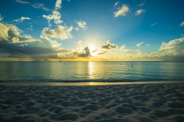 sunset on a tropical beach in the caribbean with cloudy skies and calm waters