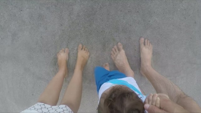 Ocean waves washing over feet family, mom, dad and son, the family spends a good time on the beach