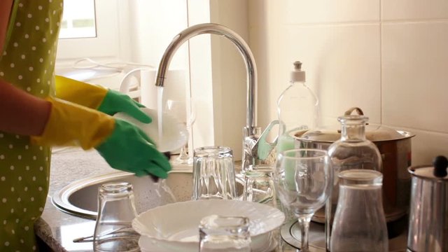  
 Close up photo of housewife in rubber gloves washing dishes in the kitchen