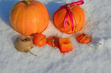 holiday Halloween orange pumpkin on the white snow, the attributes of all the saints of the day, an imprint of the hands on the snow, space for text
