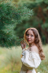 Beautiful woman in vintage dress beige. Cute girl in long dress walking in a pine forest. The style of the Queen, Princess.