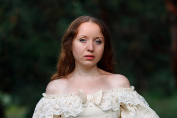 Beautiful woman in vintage dress beige. Cute girl in long dress walking in a pine forest. The style of the Queen, Princess.