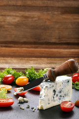 Blue cheese with tomato on wooden background and space for text